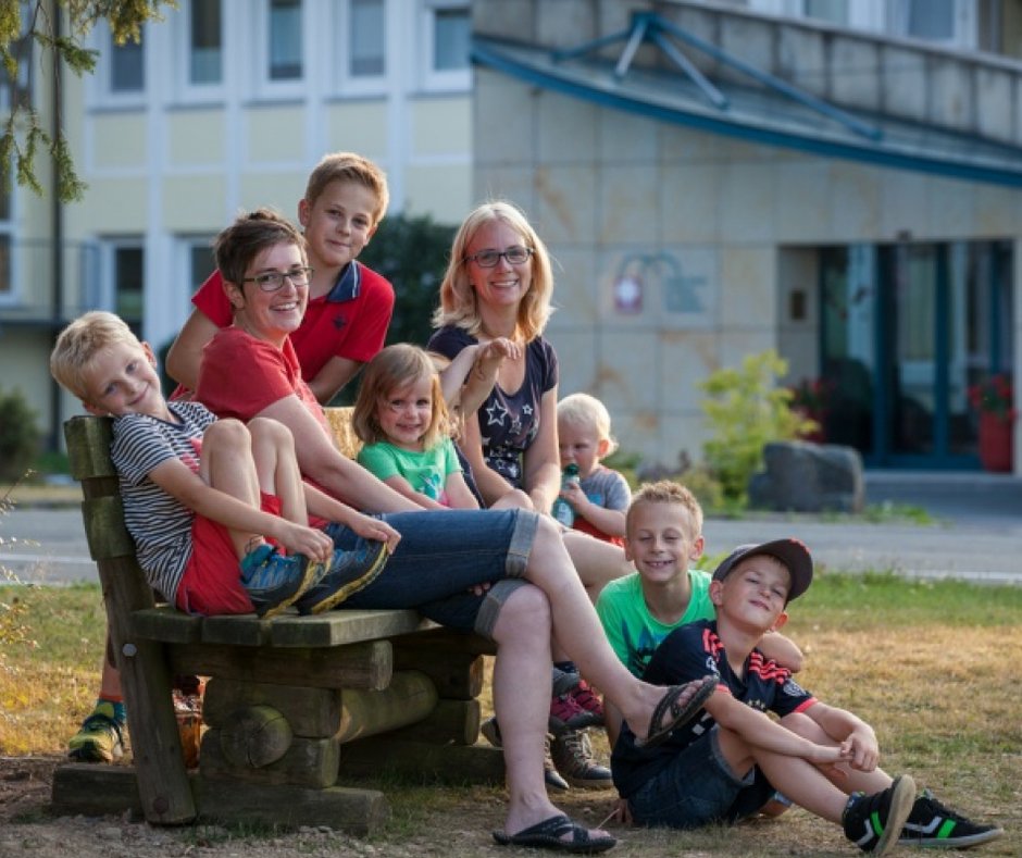 Familiengruppe sitzt gemeinsam vor einer Mutter-Kind-Klinik Mütter mit Kindern vor unserer Mutter-Kind-Klinik